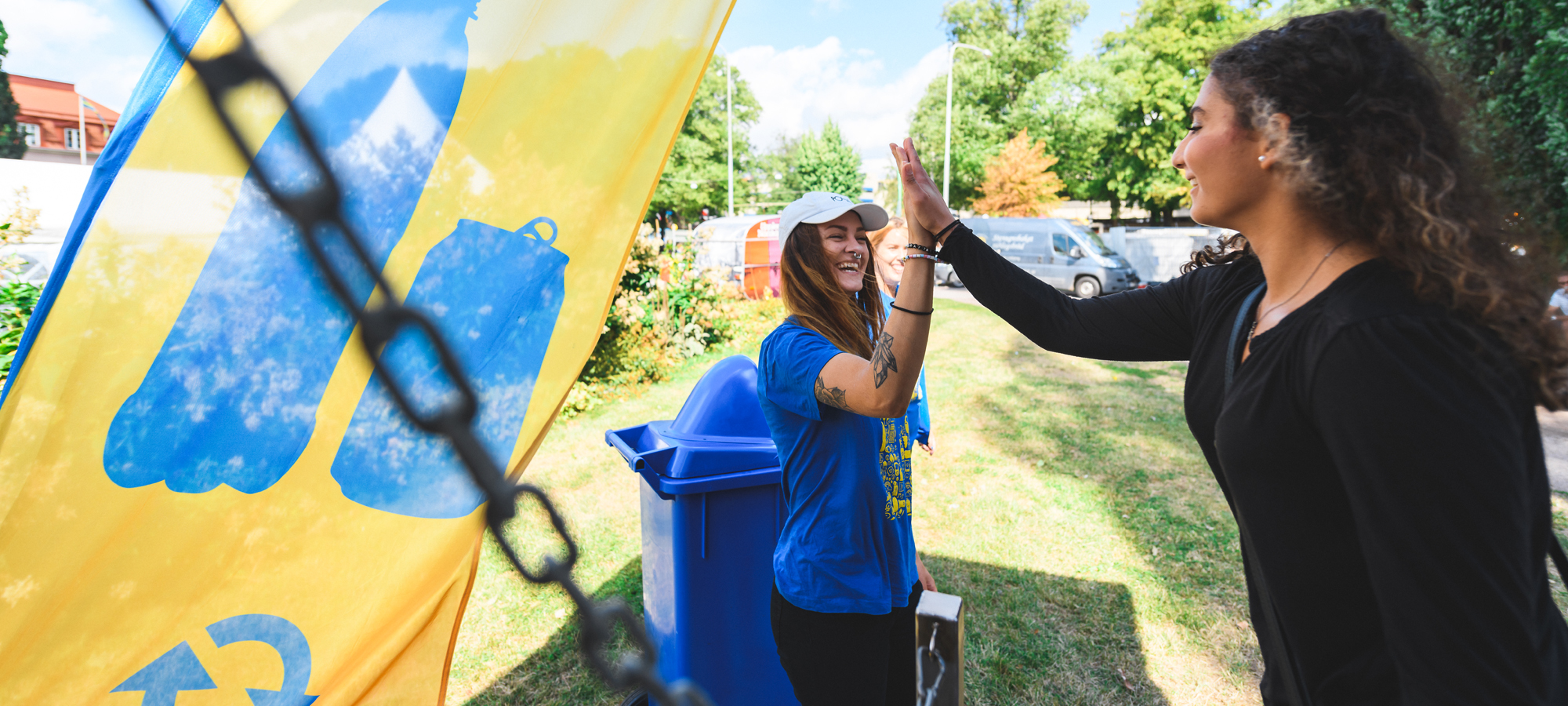 Två unga kvinnor gör high-five vid en Pantamera beachflagga