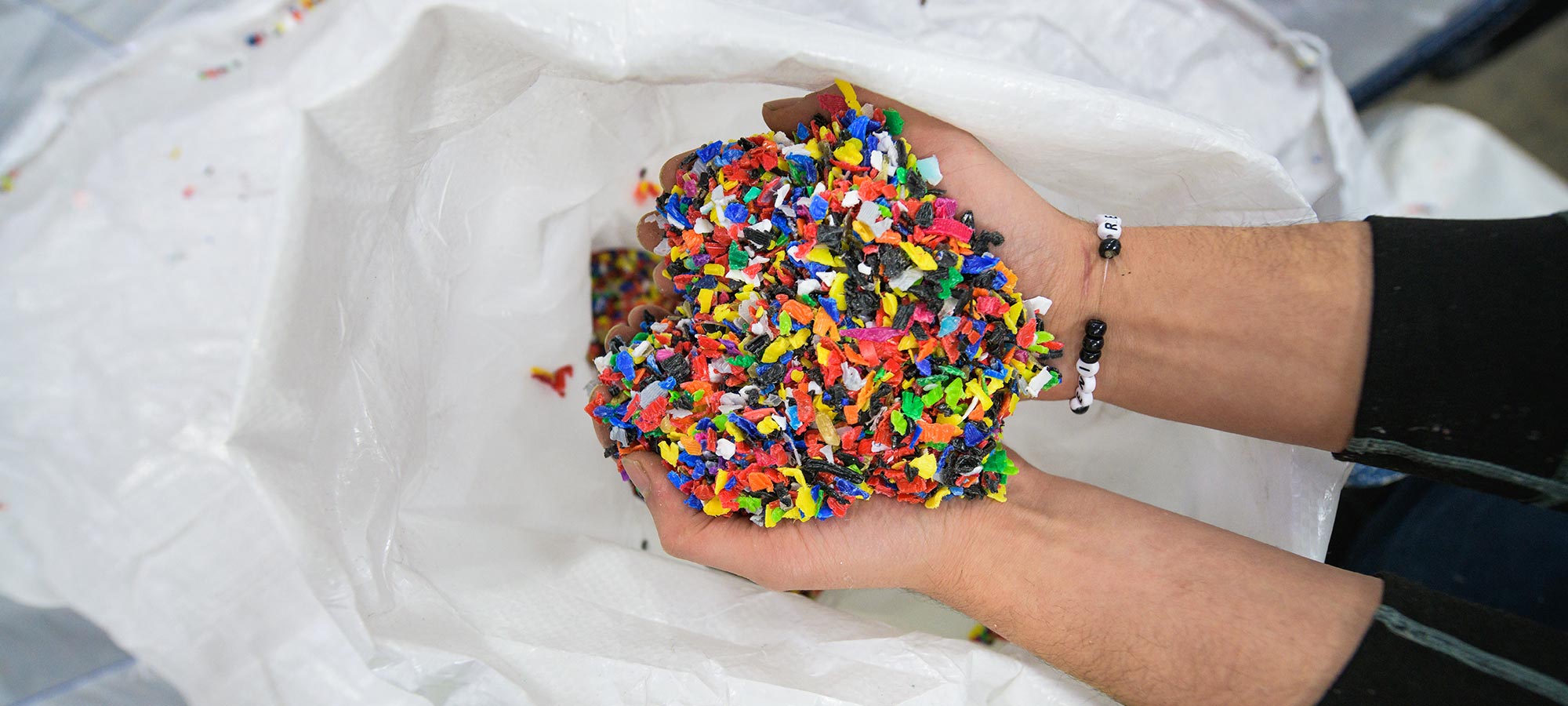 Två händer som håller i färgglada flagor av korkmaterial 